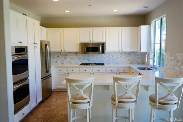 a kitchen with stainless steel appliances a stove a sink refrigerator and chairs