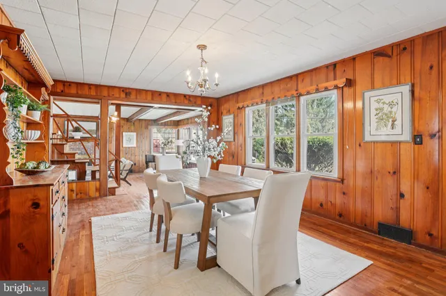 a dining room with large window wooden floor and a chandelier