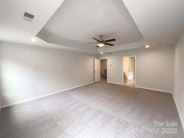 an empty room with windows and chandelier fan