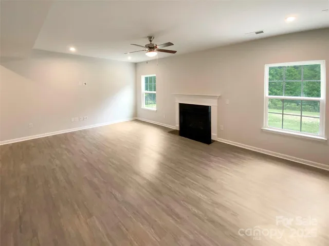 an empty room with wooden floor fireplace and windows
