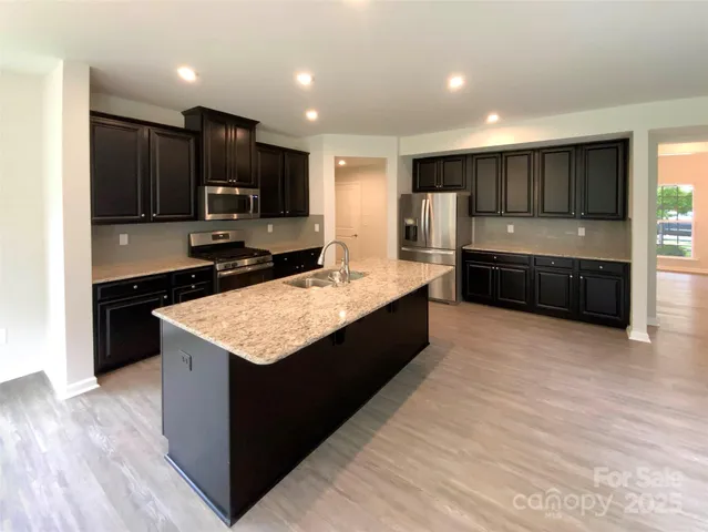 a large kitchen with kitchen island granite countertop a large counter top stainless steel appliances and cabinets