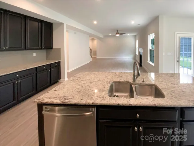 a kitchen with kitchen island granite countertop a sink and wooden cabinets