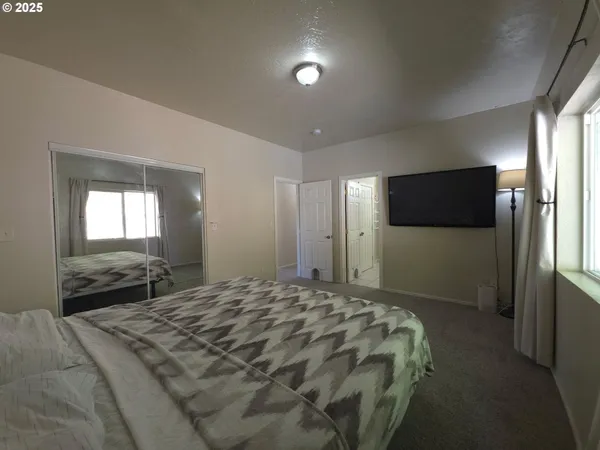 a bedroom with a bed and a flat tv screen on dresser