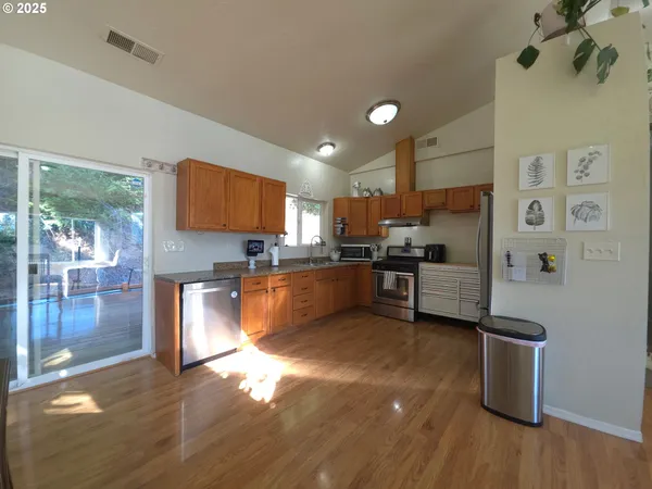 a kitchen with stainless steel appliances wooden floors and view living room