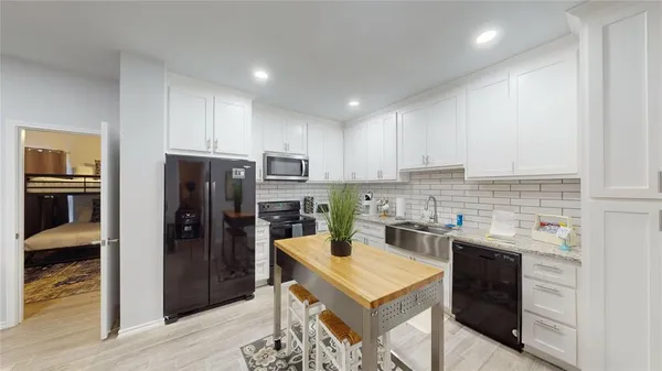 a kitchen with a refrigerator a stove a sink and dishwasher with wooden floor