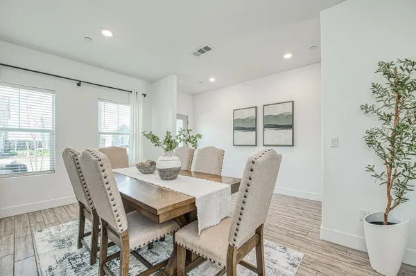 a kitchen with a table chairs wooden floors and a view of living room