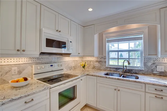 a kitchen with granite countertop white cabinets and a window