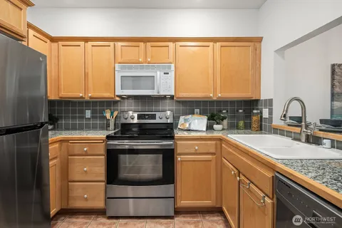 a kitchen with granite countertop a sink stainless steel appliances and cabinets