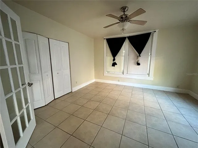 an empty room with windows and a ceiling fan