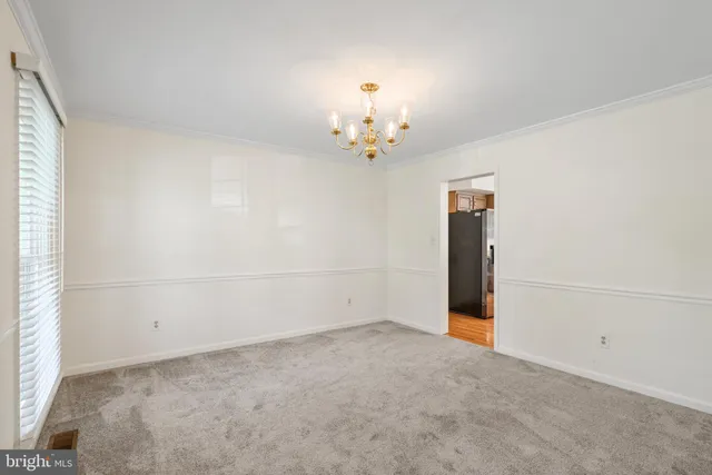 an empty room with chandelier fan and windows