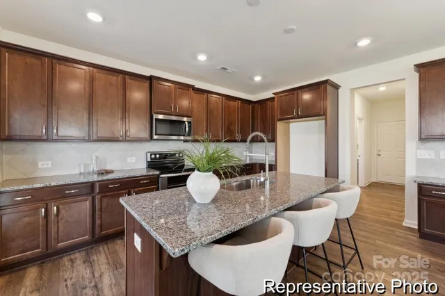 a kitchen with granite countertop a stove a sink a dining table and chairs