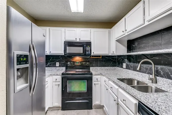 a kitchen with stainless steel appliances granite countertop a refrigerator sink and stove