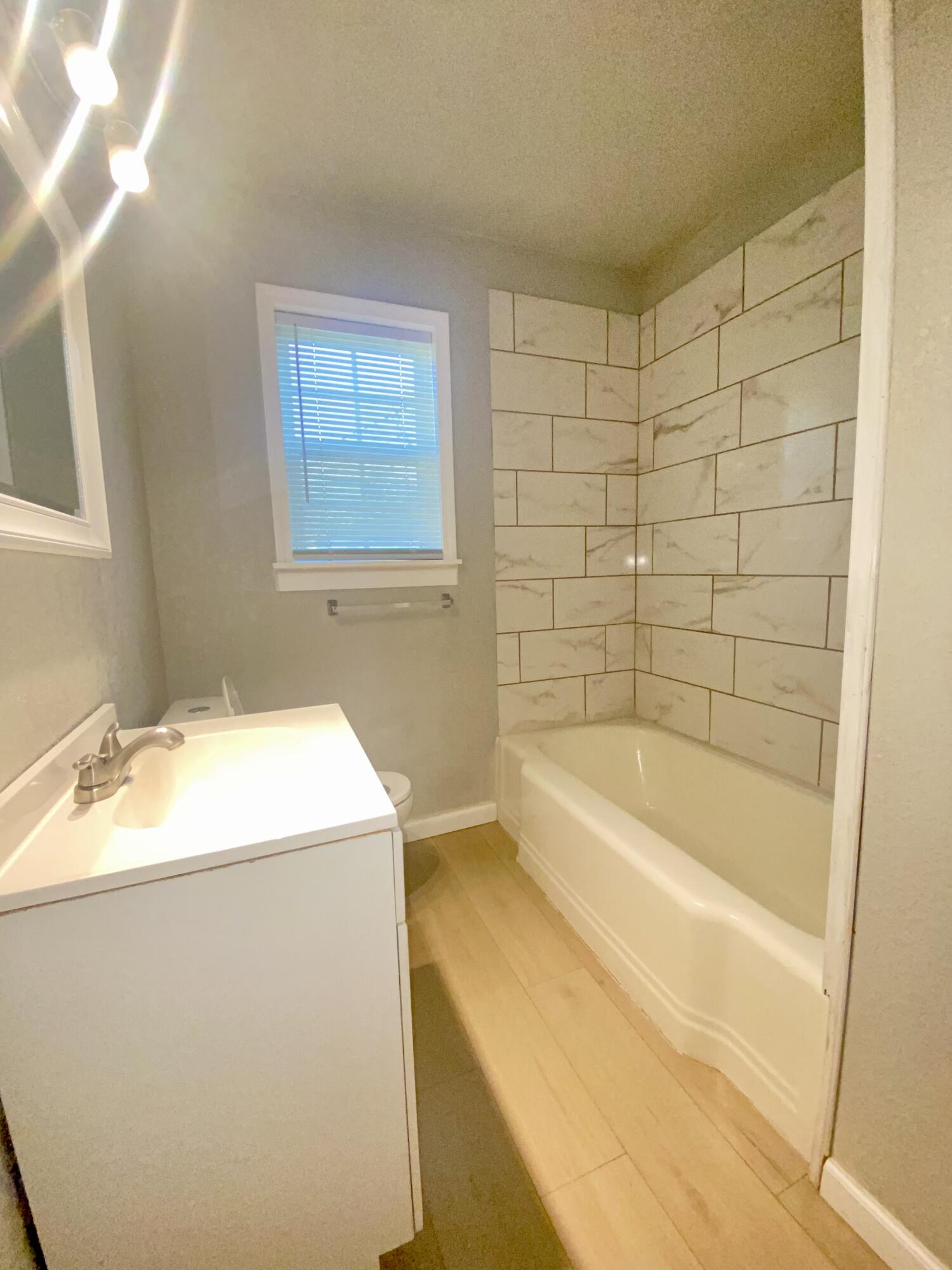 1518 40th Street Lubbock, TX 79412 - Photo 7 of 13 a bathroom with a granite countertop sink and a bathtub