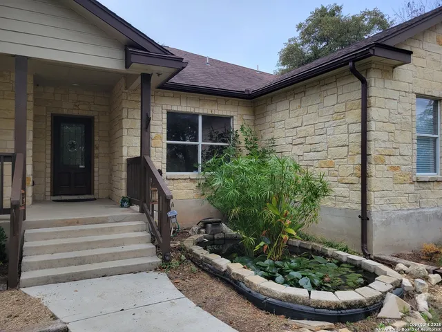 a view of a house with plants and chairs in patio