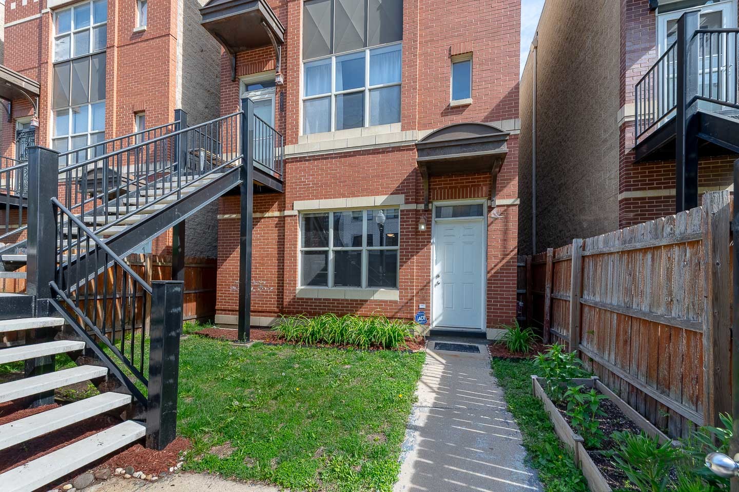 2142 West Madison Street, Unit 1 Chicago, IL 60612 - Photo 2 of 27 a view of a brick house with wooden fence next to a big yard