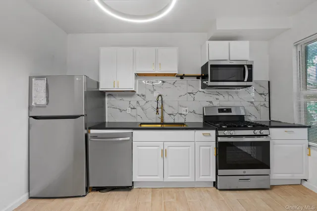 a kitchen with white cabinets and stainless steel appliances