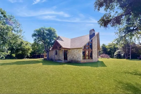 a view of a house with a big yard and large trees