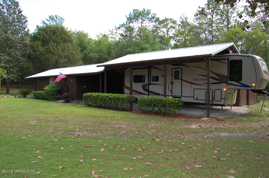 6675 Brooklyn Bay Road Keystone Heights, FL 32656 - Photo 3 of 16 a backyard of a house with wooden fence and trees