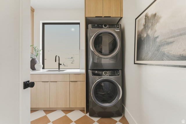 923 North Emery Lane Elk Ridge, UT 84651 - Photo 45 of 101 Laundry room featuring a stacked washer and dryer, light wood-finish cabinetry, a white countertop with an undermount sink, a black gooseneck faucet, and checkerboard floor tiling