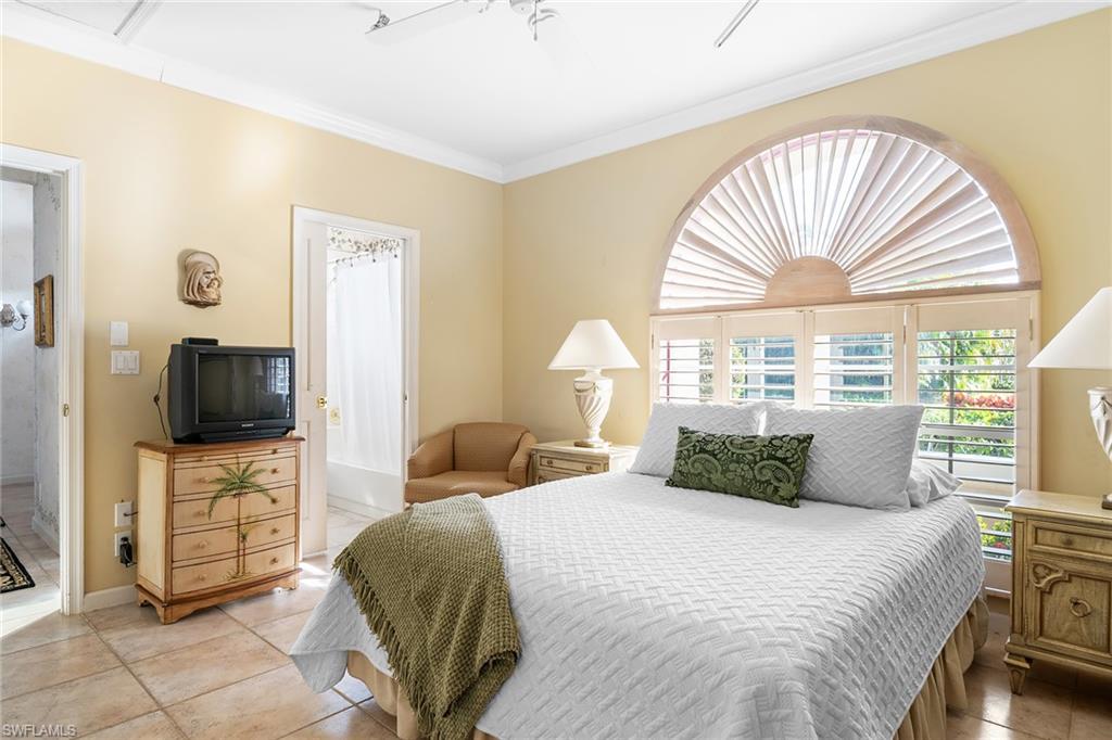2399 Northwest 24th Street Boca Raton, FL 33434 - Photo 16 of 23 Tiled bedroom featuring ensuite bathroom, ceiling fan, and ornamental molding