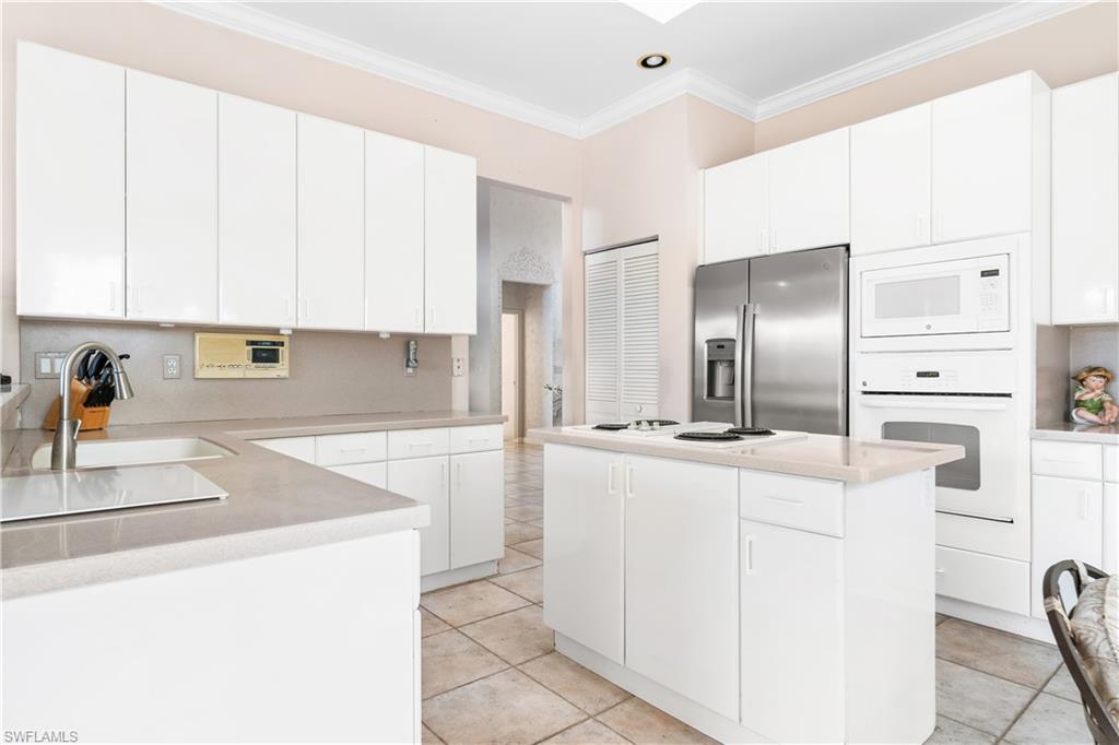 2399 Northwest 24th Street Boca Raton, FL 33434 - Photo 8 of 23 Kitchen featuring a center island, white appliances, sink, and white cabinetry