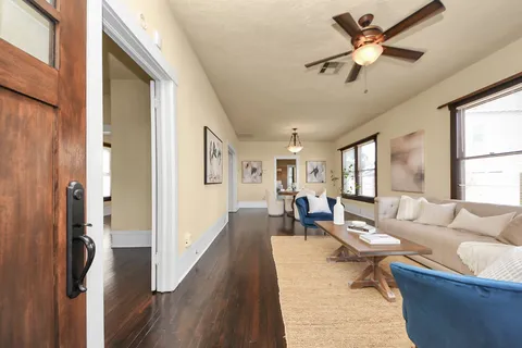 a living room with couches and a dining table with wooden floor