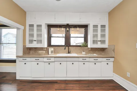 a open kitchen with white cabinets and wooden floor