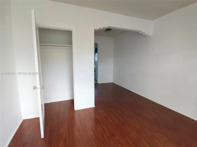 an empty room with wooden floor and closet