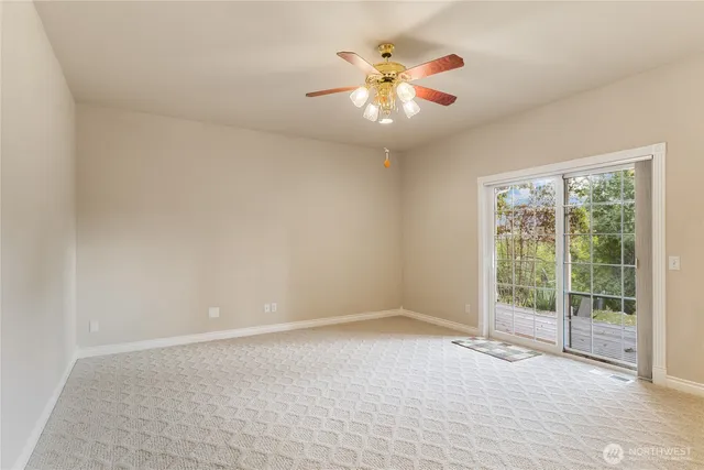 an empty room with chandelier fan and windows