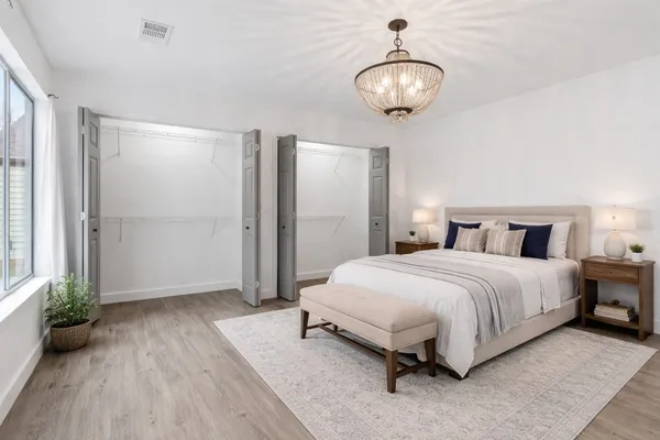 a spacious bedroom with a bed and a chandelier