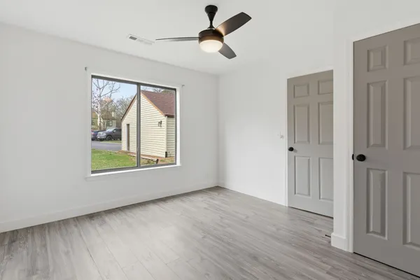 a view of an empty room with a window and wooden floor