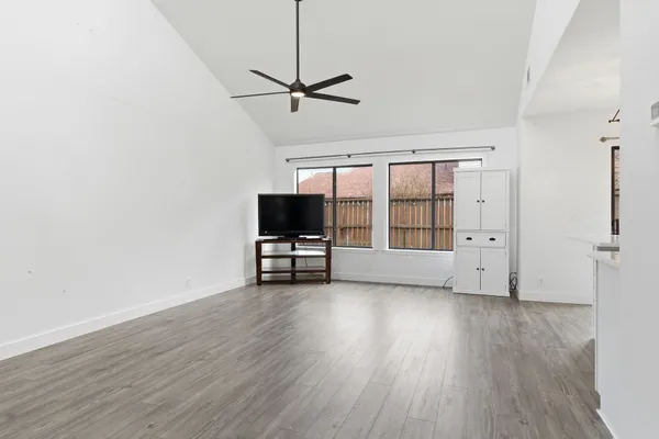 a view of an empty room with a window and wooden floor