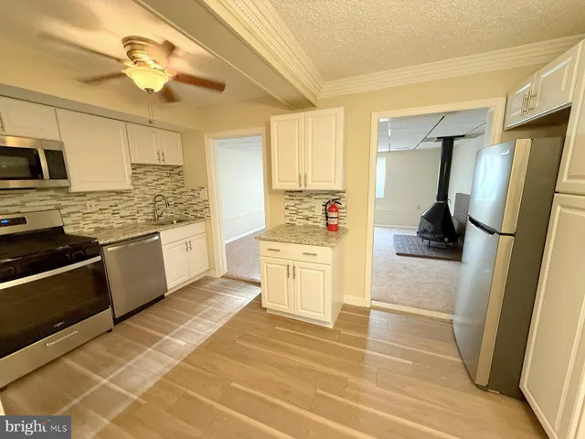 a kitchen with stainless steel appliances kitchen island granite countertop a refrigerator and a stove top oven