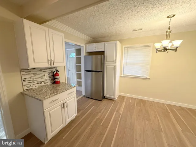 a kitchen with granite countertop a refrigerator and a stove top oven
