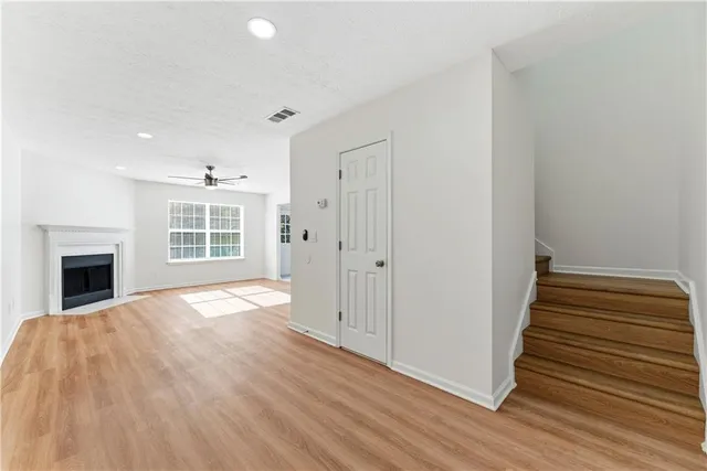 a view of empty room with wooden floor and kitchen view