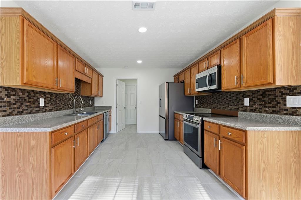 1500 Keystone Drive Conley, GA 30288 - Photo 9 of 25 a large kitchen with stainless steel appliances granite countertop a stove a sink and a refrigerator