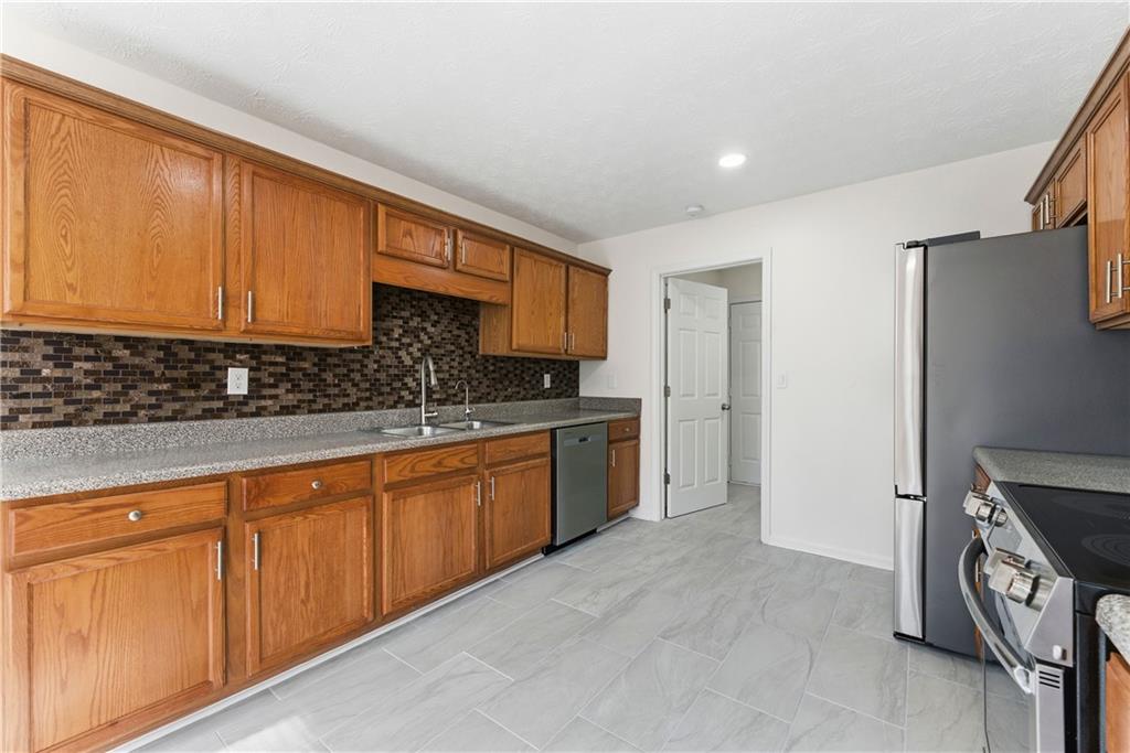 1500 Keystone Drive Conley, GA 30288 - Photo 10 of 25 a kitchen with stainless steel appliances granite countertop a stove a sink and a refrigerator with cabinets