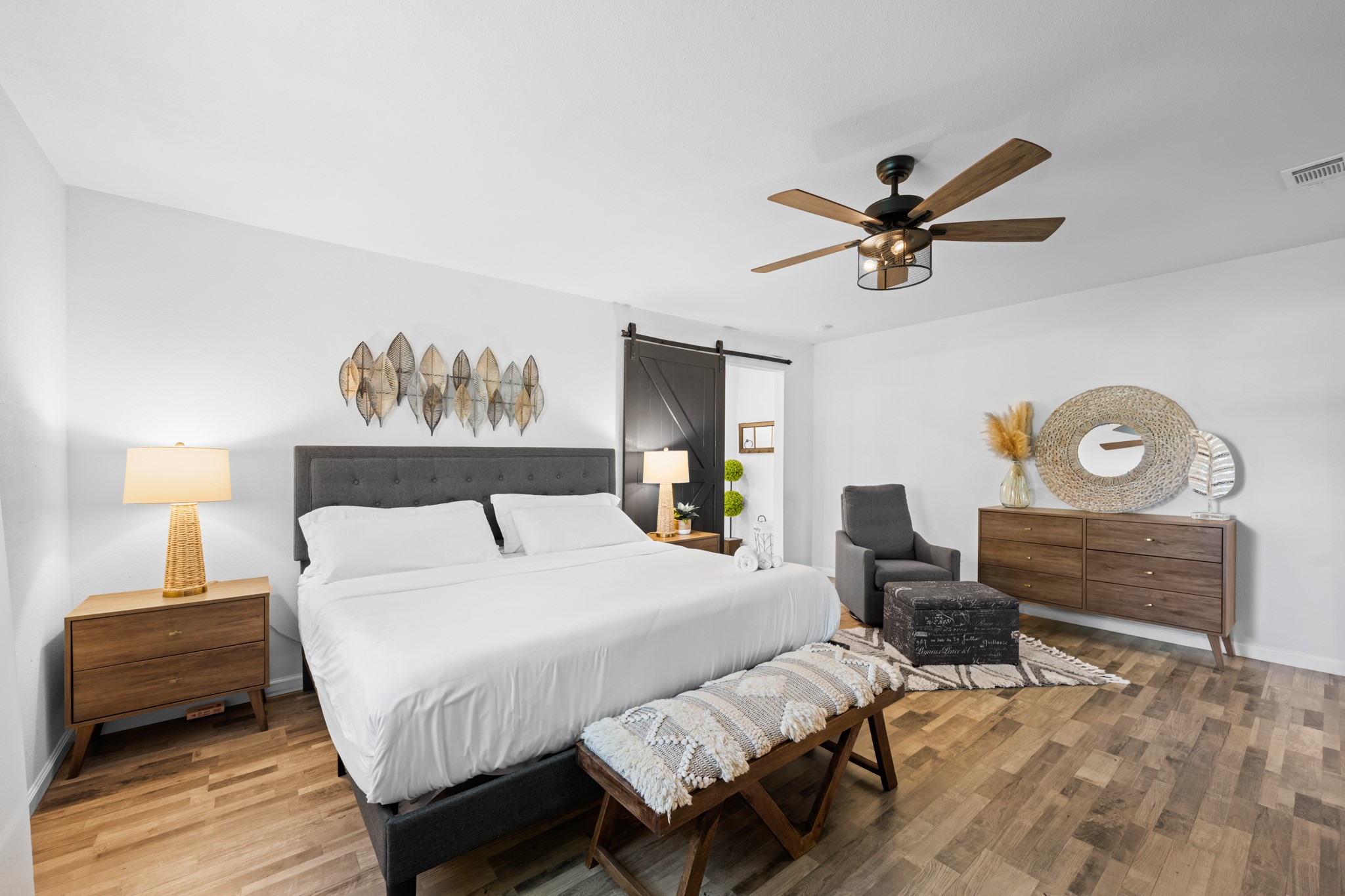 729 Kyle Angleton, TX 77515 - Photo 20 of 36 This inviting bedroom features a spacious layout with modern decor, a comfortable bed, stylish wooden furniture, and a ceiling fan. Natural light enhances the cozy, serene atmosphere, perfect for relaxation.