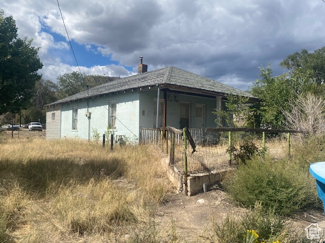 View of home's exterior with a chimney and covered porch
