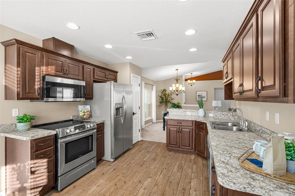 5346 Pierpoint Avenue Spring Hill, FL 34608 - Photo 15 of 41 a kitchen with stainless steel appliances granite countertop wooden cabinets a stove a sink and a refrigerator