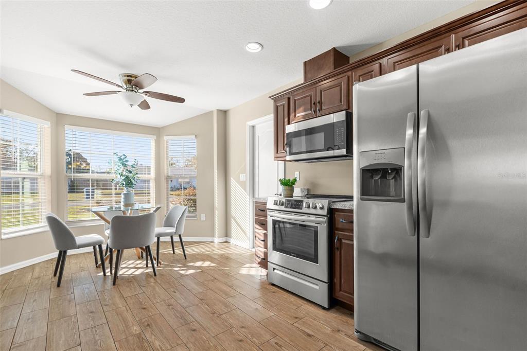 5346 Pierpoint Avenue Spring Hill, FL 34608 - Photo 16 of 41 a kitchen with stainless steel appliances a dining table chairs refrigerator and wooden floor