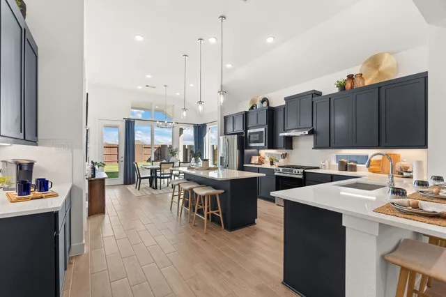 a open kitchen with cabinets a sink dishwasher and a stove with wooden floor