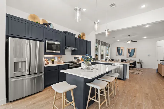 a kitchen with a dining table cabinets appliances and wooden floor