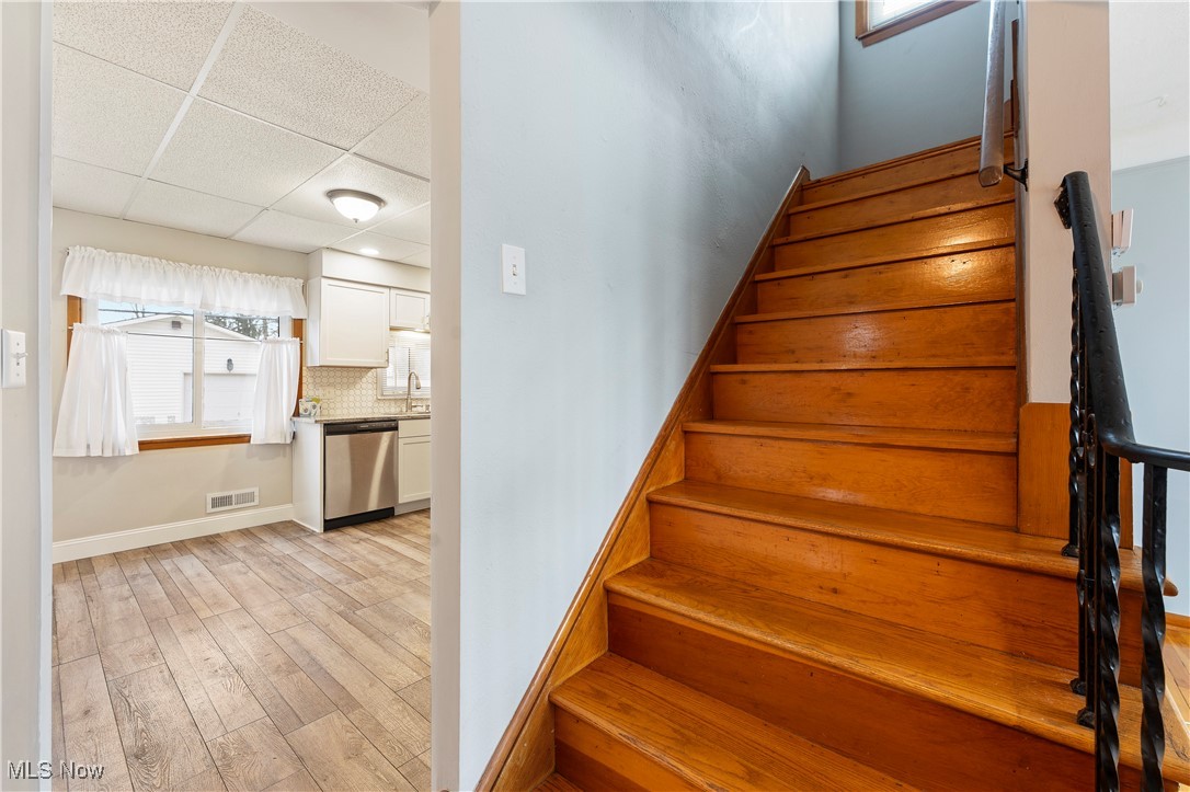 3105 Snow Road Cleveland, OH 44134 - Photo 19 of 38 Stairs featuring a paneled ceiling, wood finished floors, baseboards, and visible vents