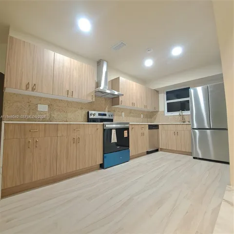 a kitchen with stainless steel appliances granite countertop a refrigerator sink a stove and white cabinets