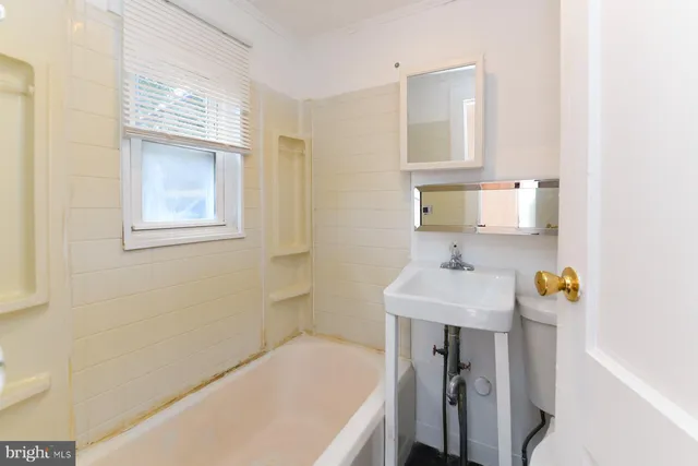 a bathroom with a sink a bathtub and a window