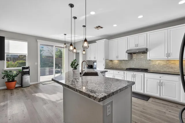 a kitchen with stainless steel appliances granite countertop a sink a stove and a wooden floors