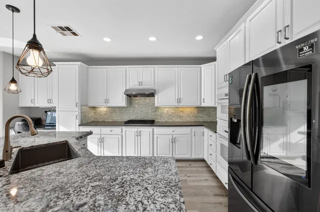 a kitchen with stainless steel appliances granite countertop a sink a stove and a refrigerator
