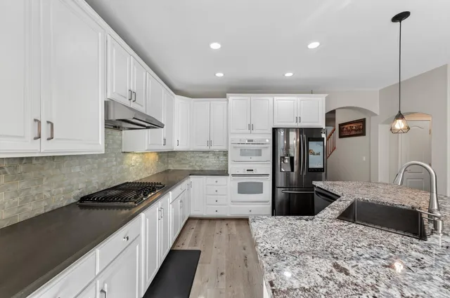 a kitchen with stainless steel appliances granite countertop a sink stove and refrigerator