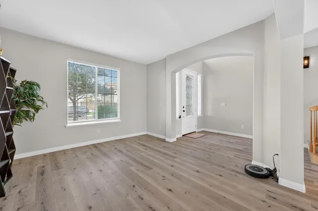 an empty room with wooden floor and windows